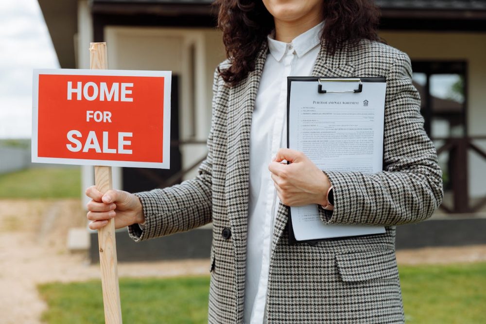 close-up-of-a-woman-holding-a-home-for-sale-sign